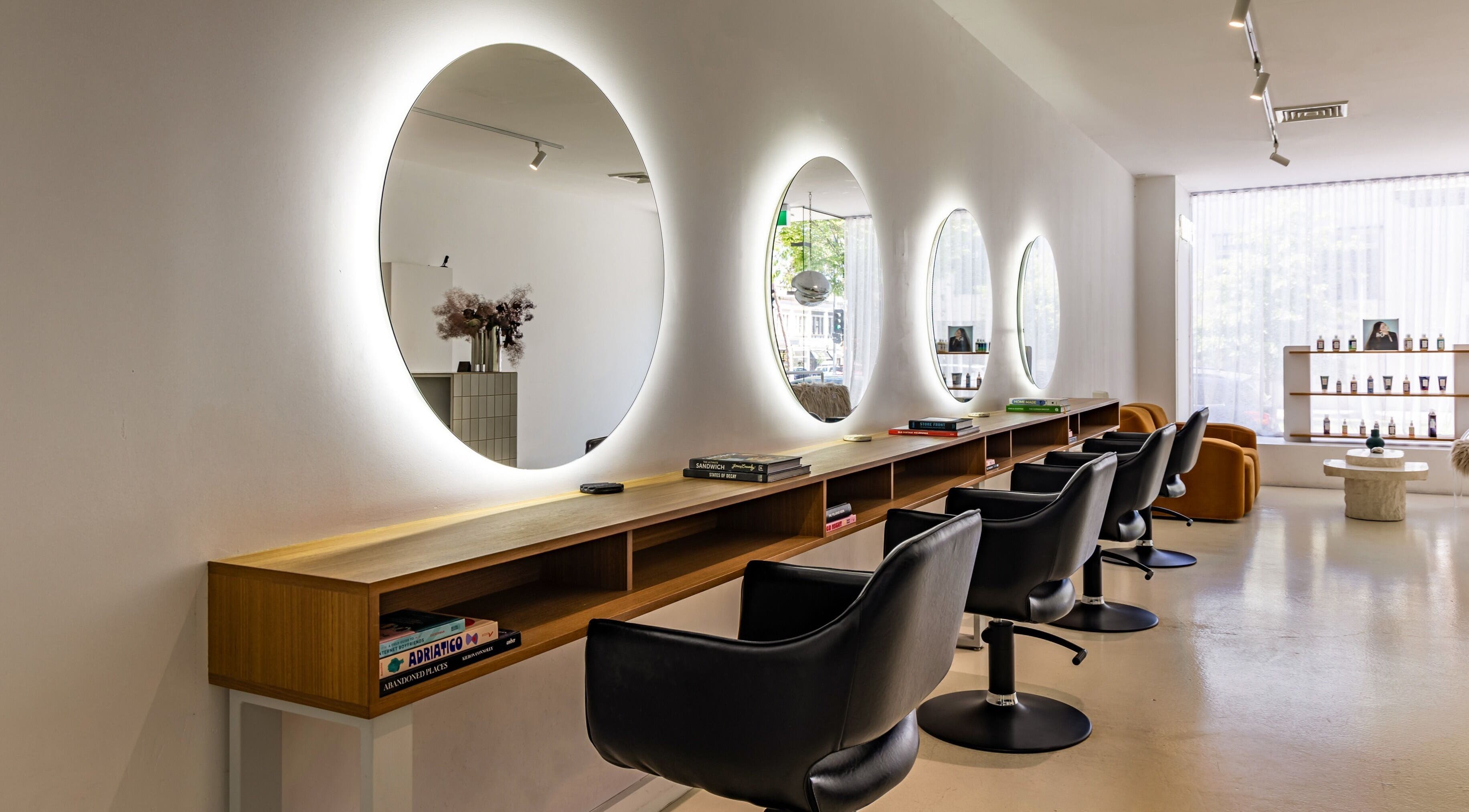 Elegant salon interior at WAVES in Melbourne, Victoria, AU highlighting modern chairs and glowing mirrors.