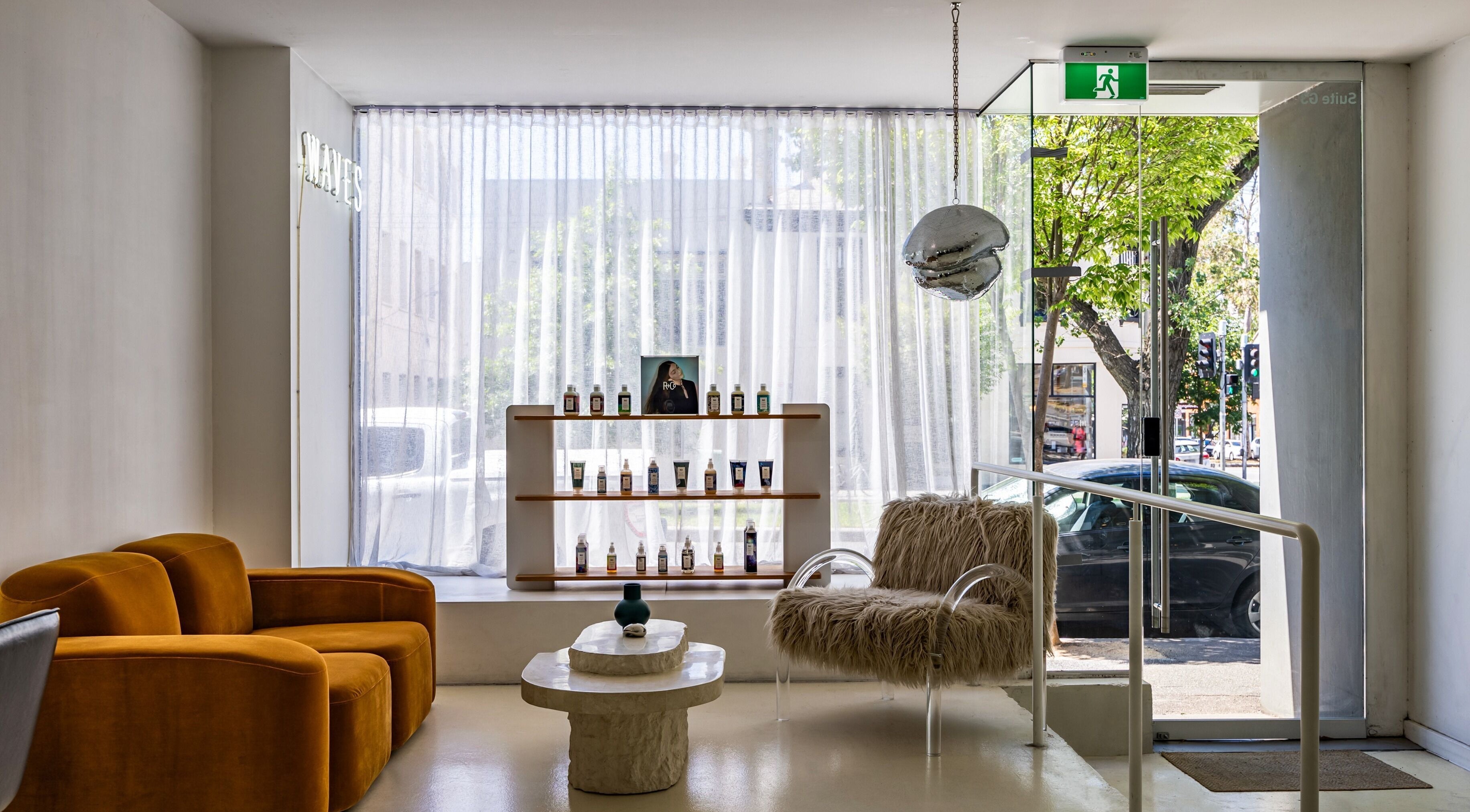 Cozy lobby at WAVES in Melbourne, Victoria, AU with modern decor, velvet sofas, and beauty products on display.