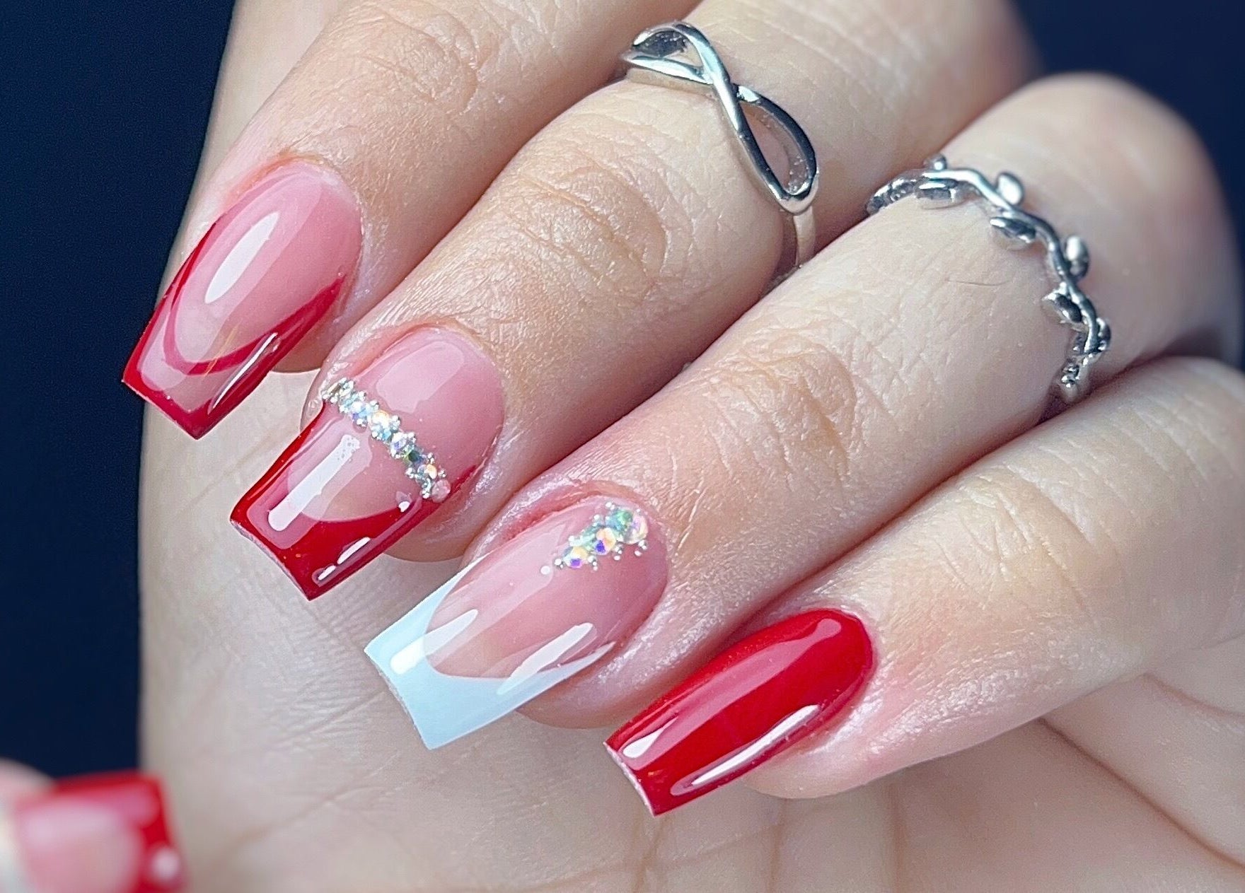 Uñas acrílicas rojas brillantes en Yoss Nails, Memphis, Tennessee, US, con detalles de brillo.