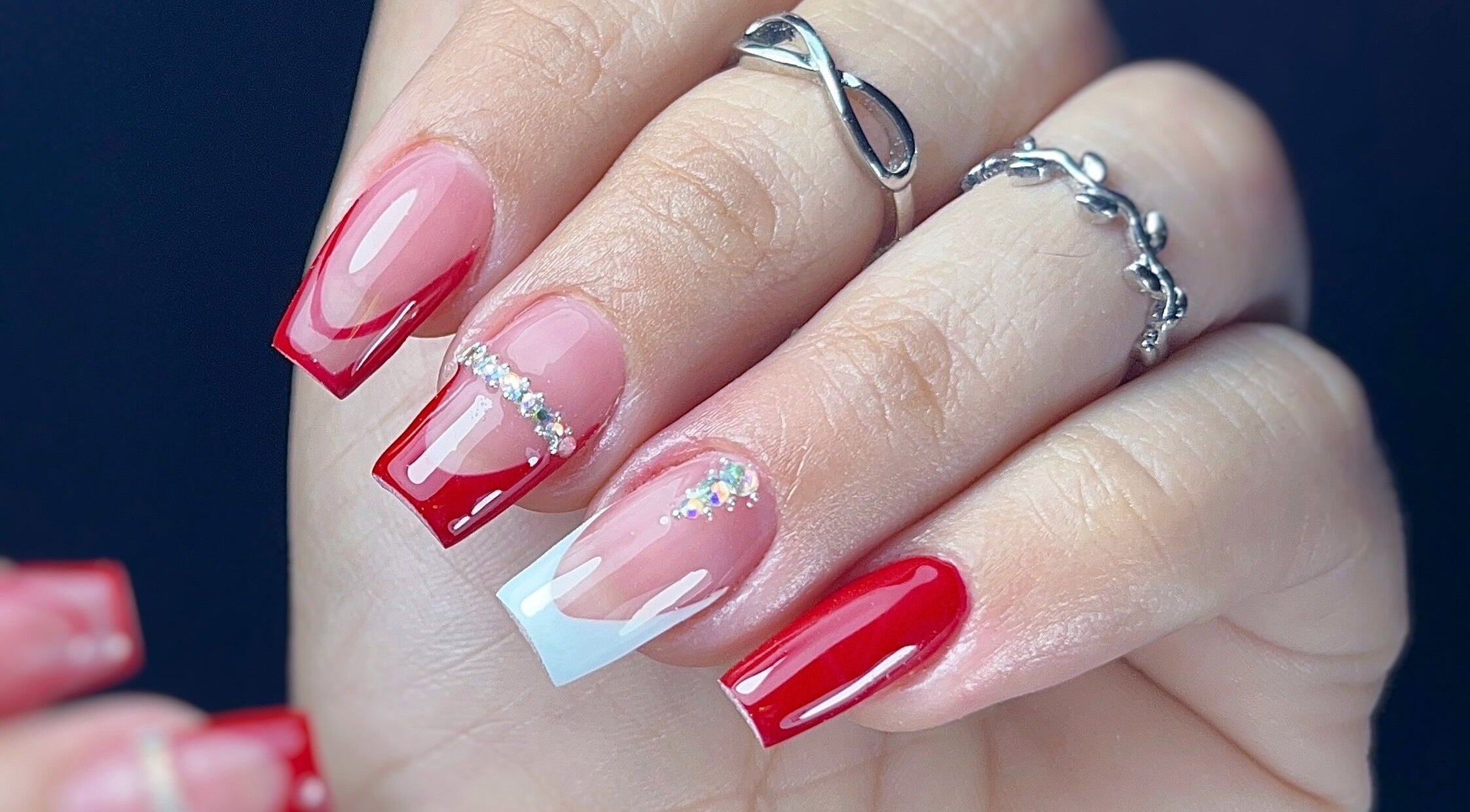 Uñas acrílicas rojas brillantes en Yoss Nails, Memphis, Tennessee, US, con detalles de brillo.