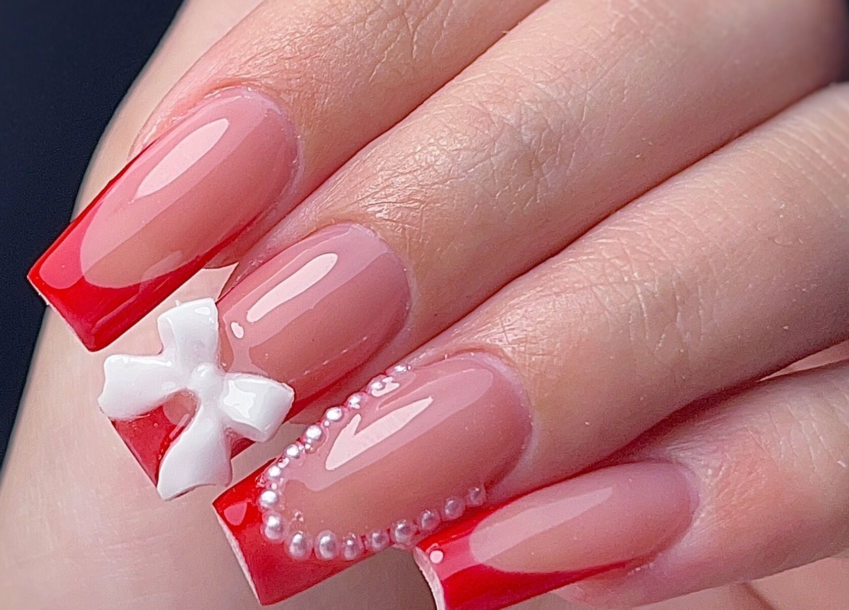 Diseño de uñas en Yoss Nails, Memphis, Tennessee, US, con esmalte rojo y detalles en pedrería.