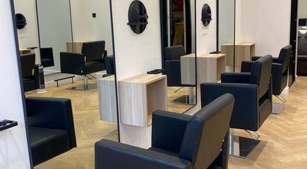Modern salon interior at Ash Pro Hair in Glasgow, Scotland, GB with sleek black chairs and large mirrors.