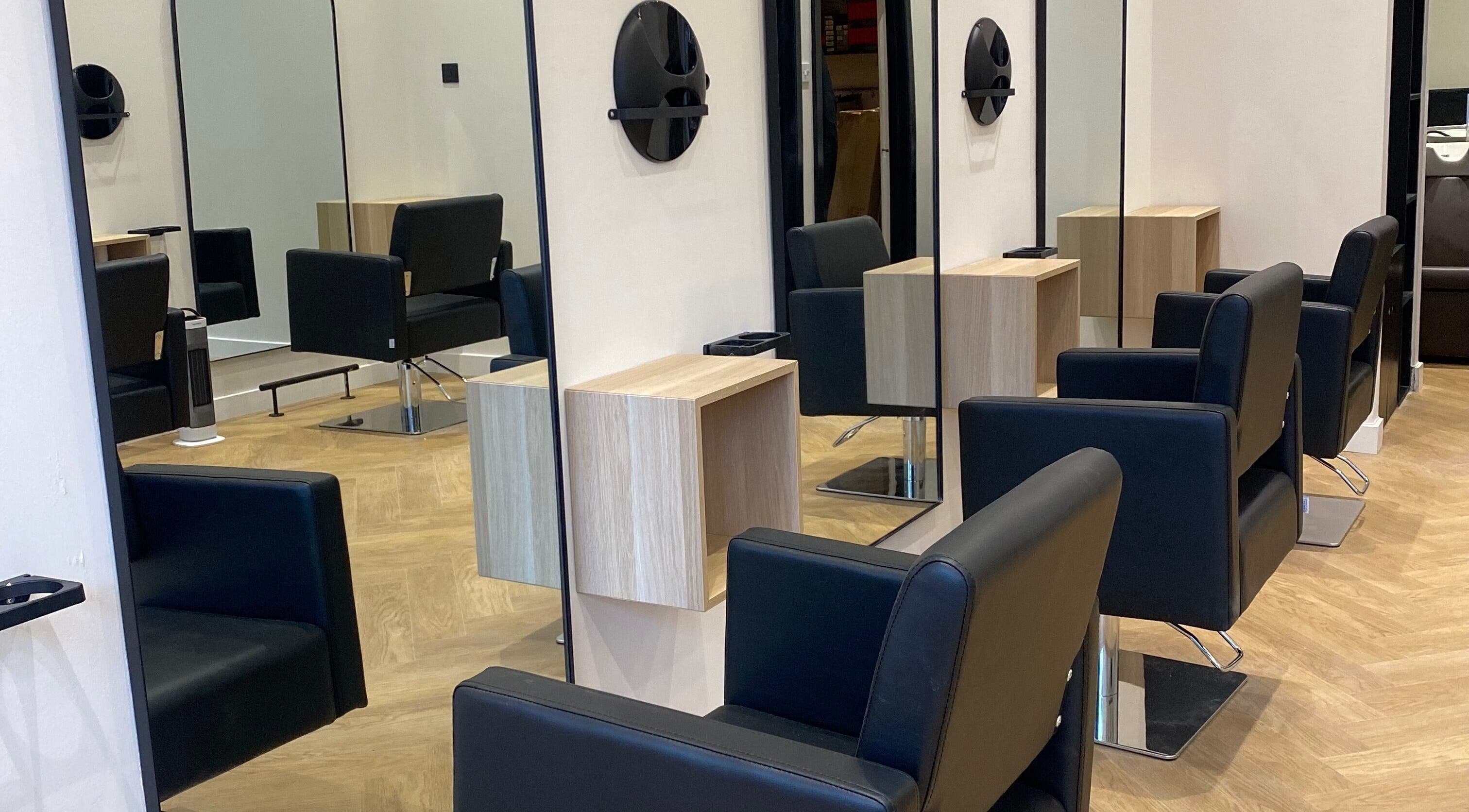 Modern salon interior at Ash Pro Hair in Glasgow, Scotland, GB with sleek black chairs and large mirrors.