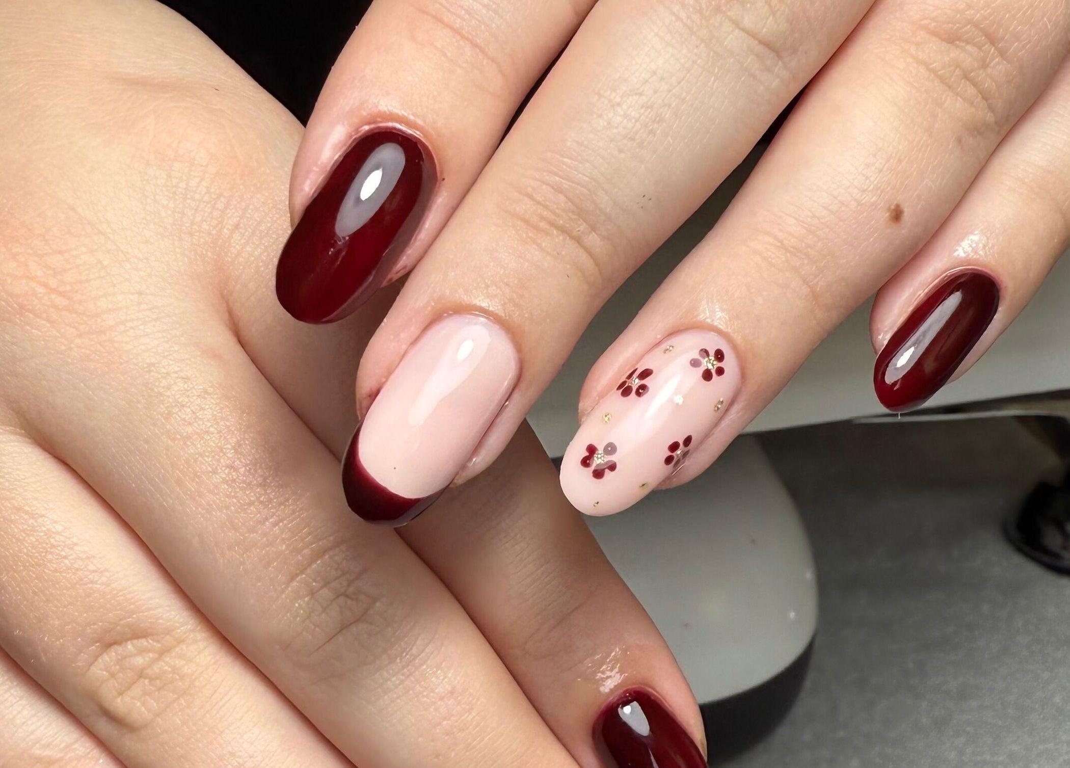 Elegant cherry nail art at The Nail Vault, Plymouth, England, GB, showcasing rich burgundy polish with floral accents.