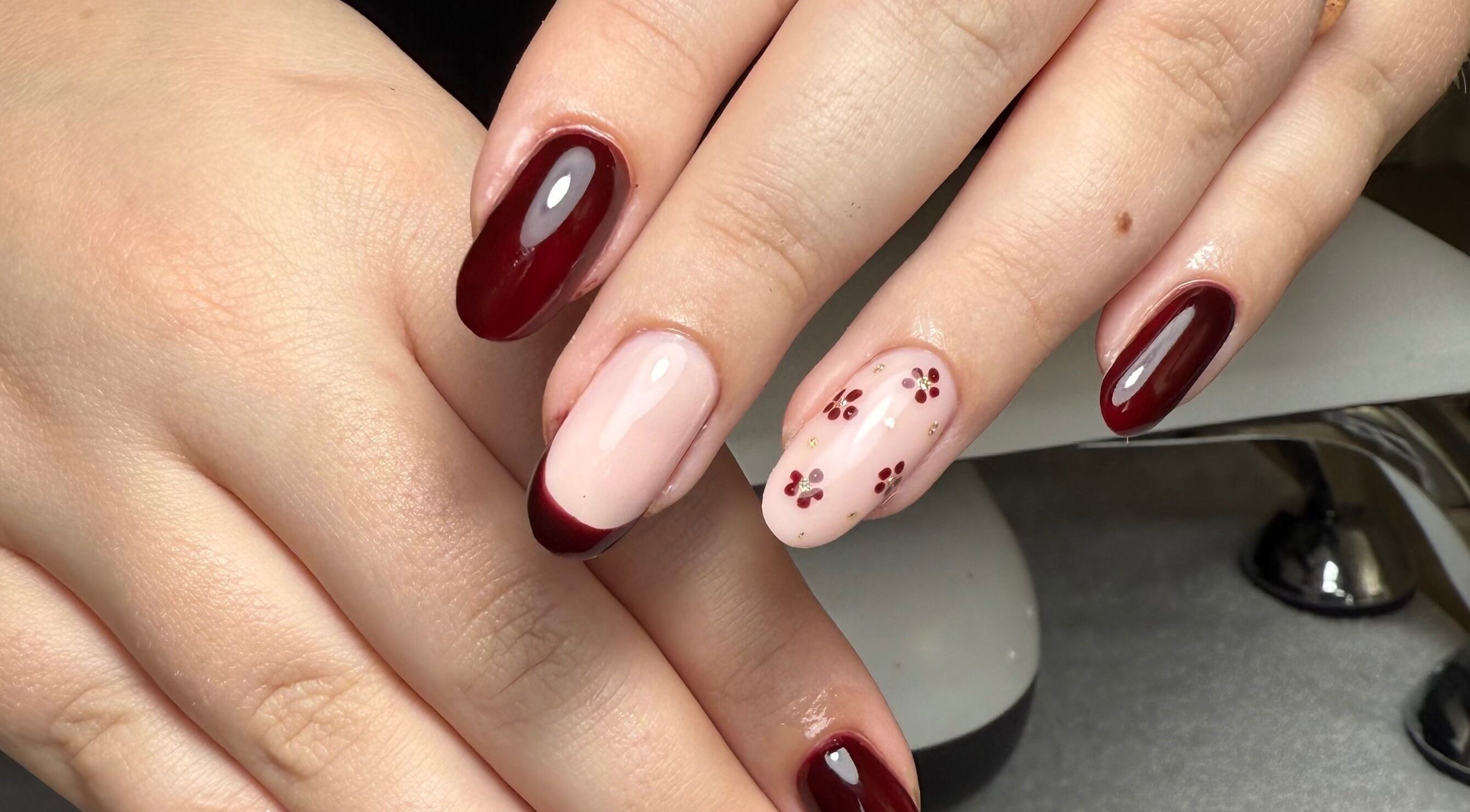 Elegant cherry nail art at The Nail Vault, Plymouth, England, GB, showcasing rich burgundy polish with floral accents.