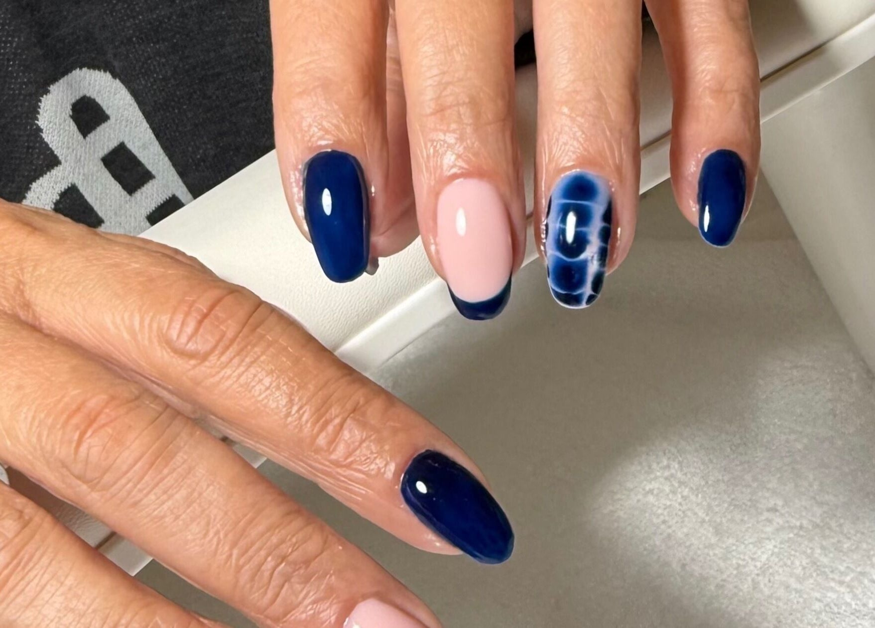 Hand with elegant blue and pink nail art at The Nail Vault, Plymouth, England, GB.