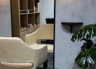 Silla de salón en Hula Studio, Ciudad De México, rodeada de plantas y productos de belleza en estantes.