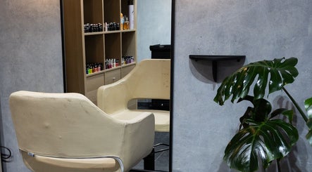 Silla de salón en Hula Studio, Ciudad De México, rodeada de plantas y productos de belleza en estantes.