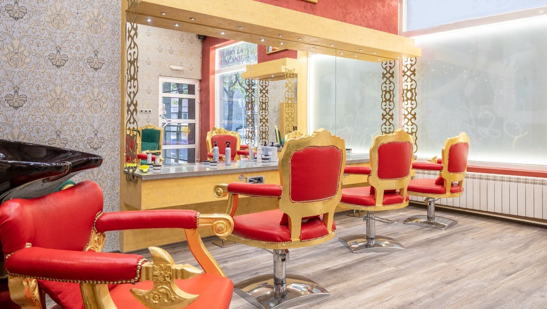 Luxurious interior of Raskoljnikov Beauty Studio in Београд, RS, featuring opulent red and gold styling chairs.