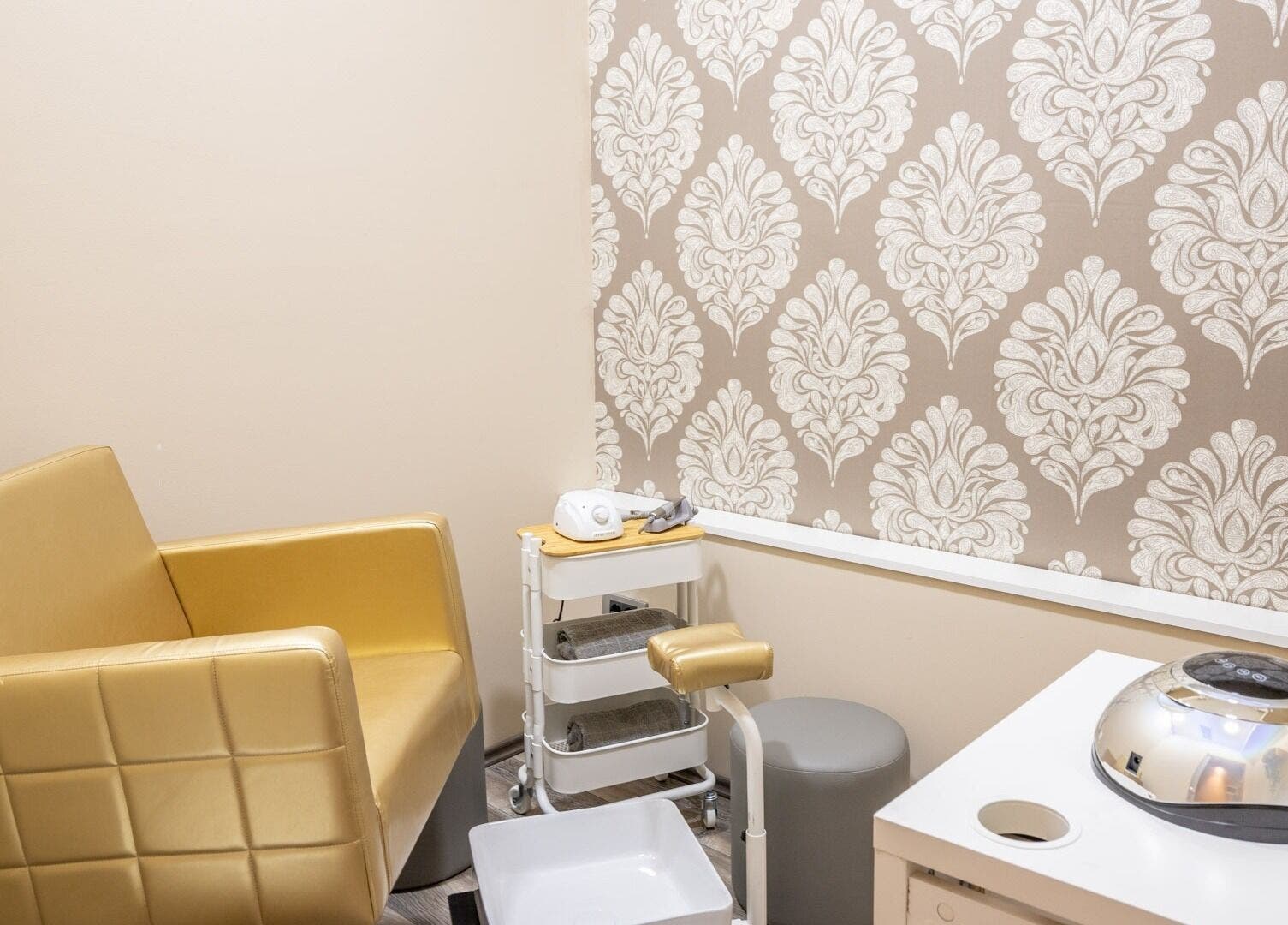 Elegant treatment room at Raskoljnikov Beauty Studio, Београд, RS, featuring a gold chair and patterned wall.