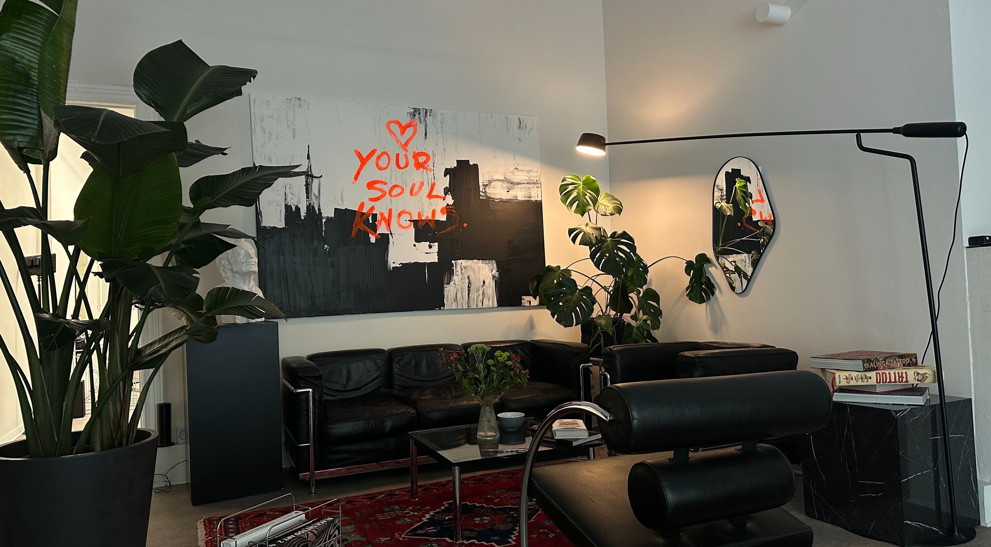 Cozy lounge at Usee Tattoo Studio, Berlin with art and plants creating a welcoming atmosphere.
