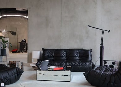 Spacious lounge at Usee Tattoo Atelier in Berlin, Berlin, DE with sleek black furniture and minimalist decor.
