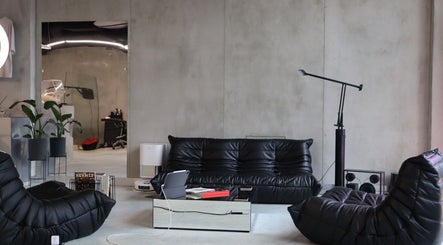 Spacious lounge at Usee Tattoo Atelier in Berlin, Berlin, DE with sleek black furniture and minimalist decor.