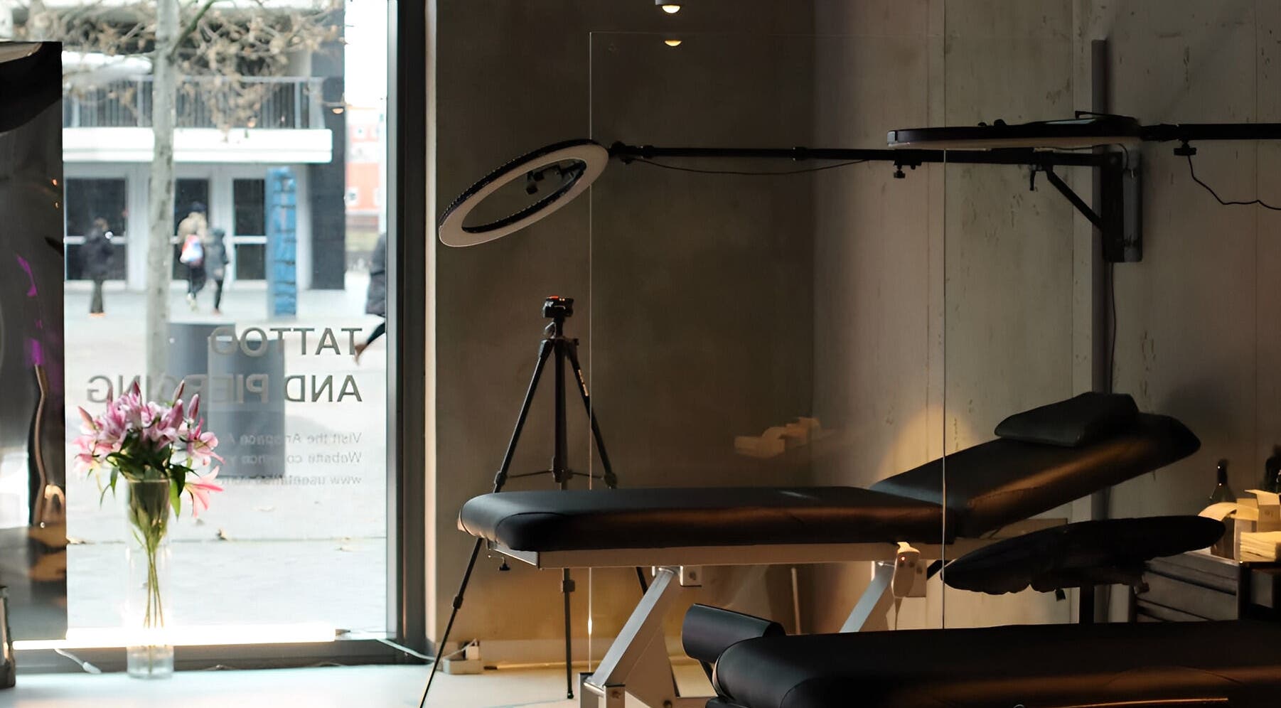 Calm interior of Usee Tattoo Atelier in Berlin, Berlin, DE, featuring a tattoo bed, tripod, and flowers.