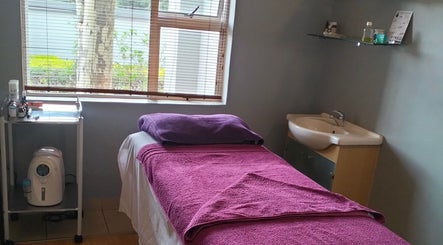 Cozy massage room at Maxima Sports Massage, Pretoria, Gauteng, ZA with purple bedding and calming decor.