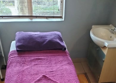 Cozy massage room at Maxima Sports Massage, Pretoria, Gauteng, ZA with plush purple towels and a sink.