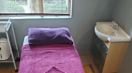 Cozy massage room at Maxima Sports Massage, Pretoria, Gauteng, ZA with plush purple towels and a sink.