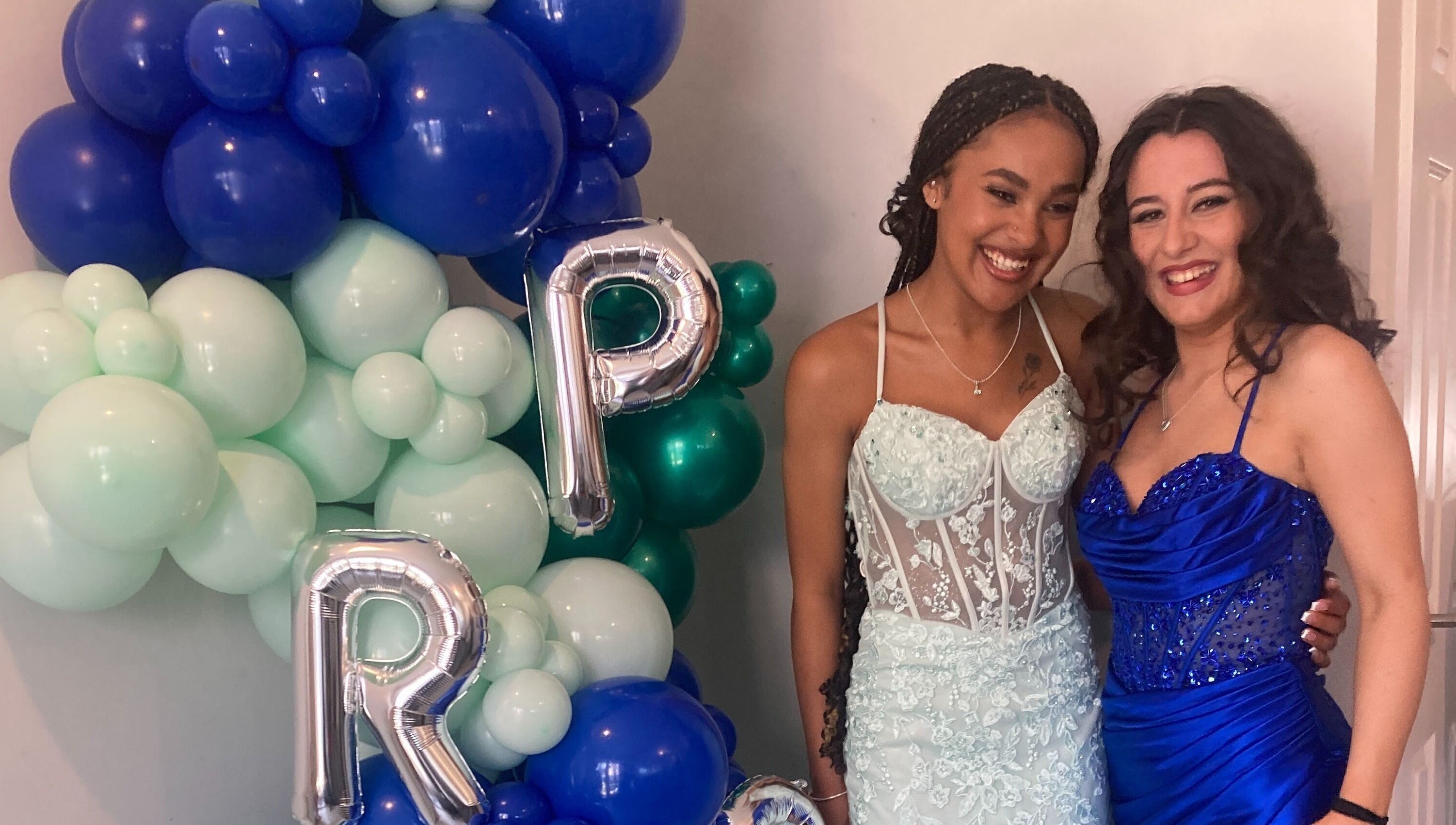 Two women in elegant dresses at Rita DeSario Make-Up Artist, Southampton, England, GB, with festive balloons.