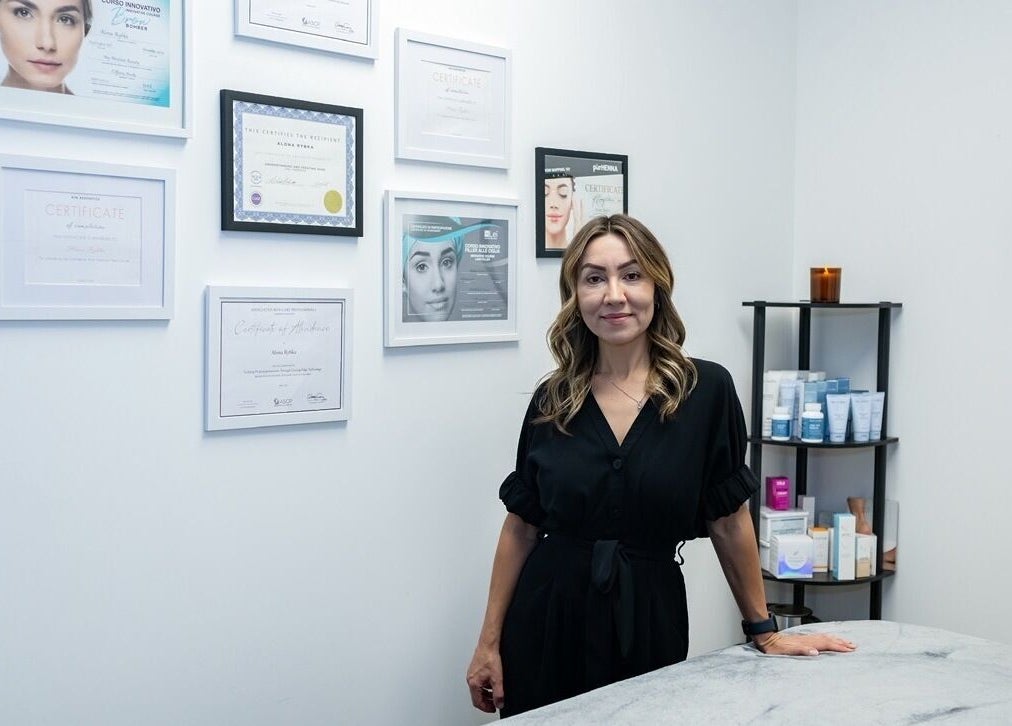 A beauty specialist at Face Essence Studio in Novato, California, US, stands by certificates in a serene treatment room.