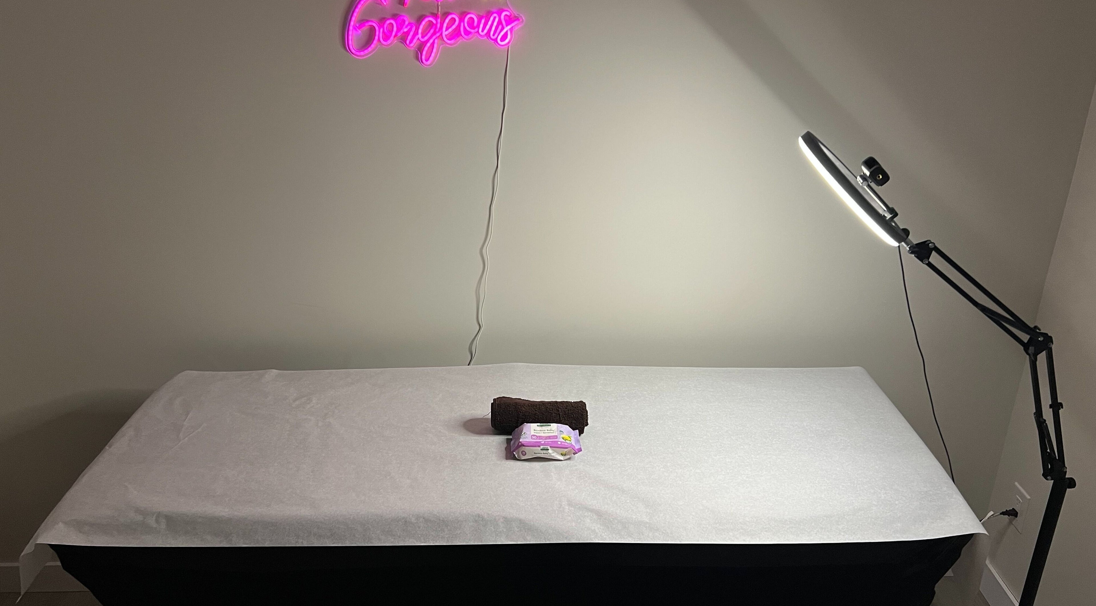 Treatment table at Comfort Wax Studio in Edmonton, Alberta, CA with neon sign and lamp.