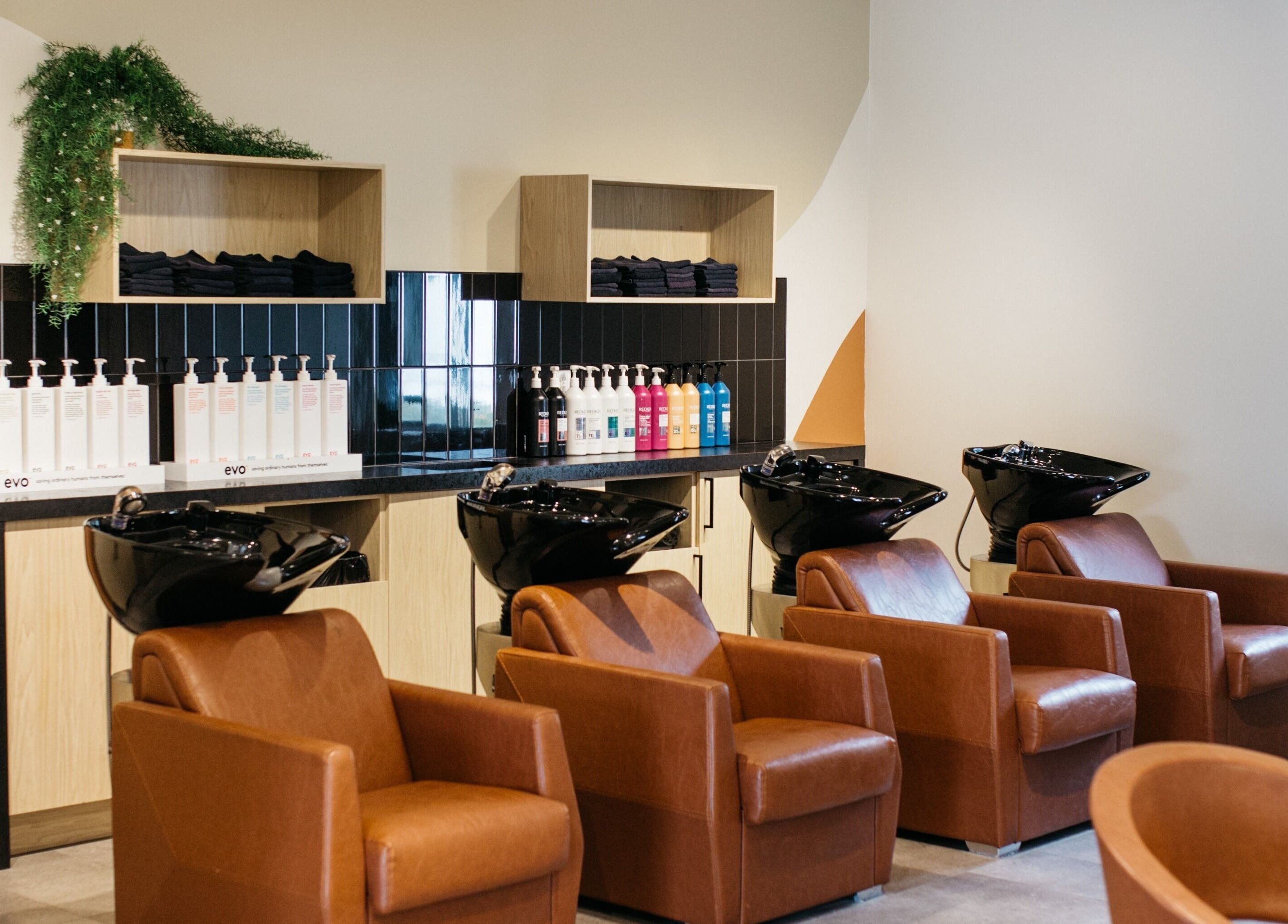 Stations de lavage élégantes chez Salon KANVA à Boisbriand, Québec, CA, avec des sièges marron et miroirs.