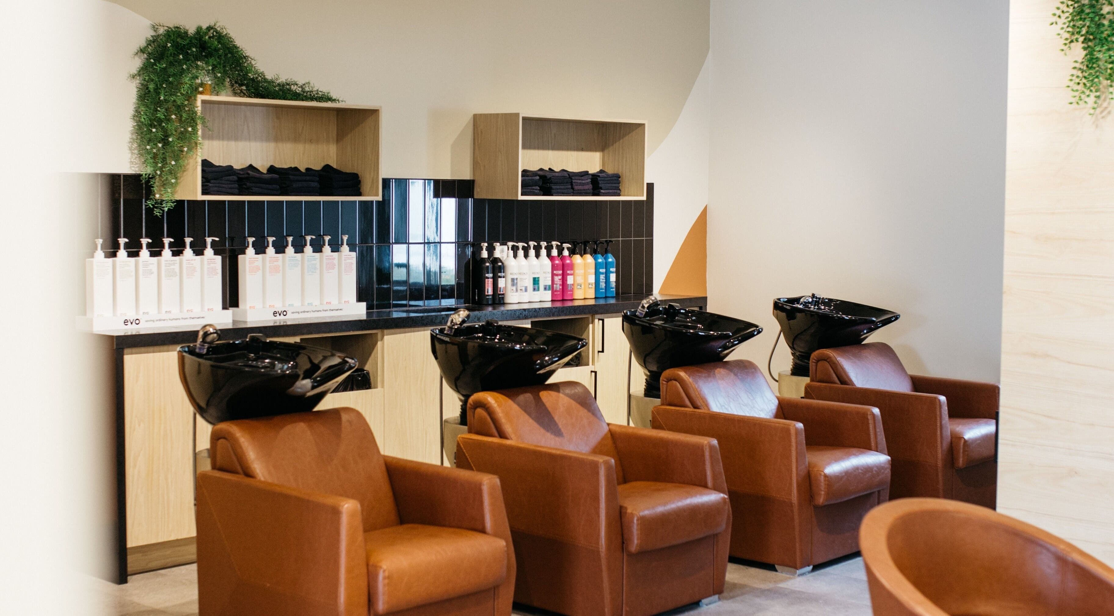Stations de lavage élégantes chez Salon KANVA à Boisbriand, Québec, CA, avec des sièges marron et miroirs.