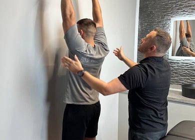 Therapist assists man in stretching at First Place Physiotherapy, Fleet, England, GB.