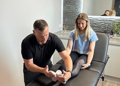 Therapist assisting client at First Place Physiotherapy, Fleet, England, GB for foot treatment.