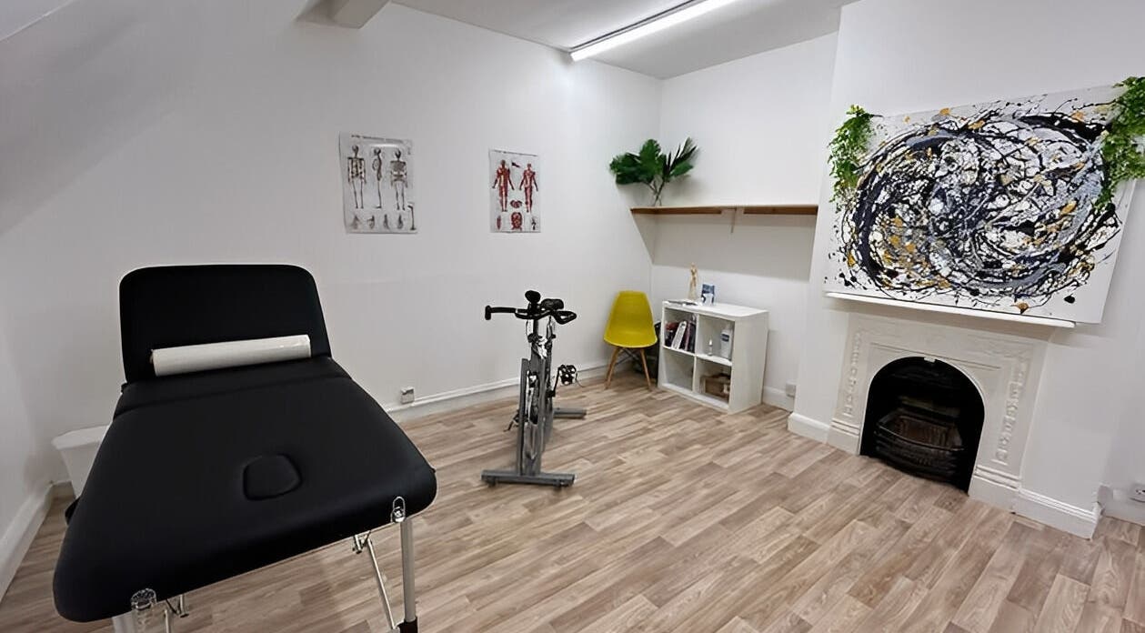 First Place Physiotherapy room in Fleet, England, GB featuring a massage bed, exercise bike, and modern art.
