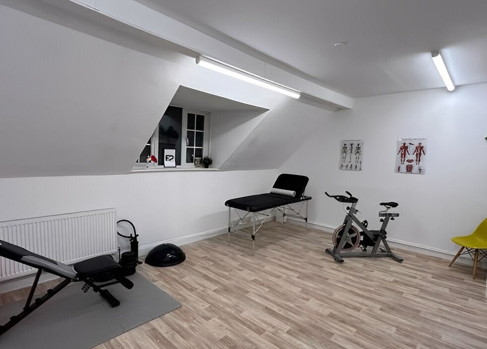 Modern therapy room at First Place Physiotherapy in Fleet, England, with gym equipment and treatment bed.