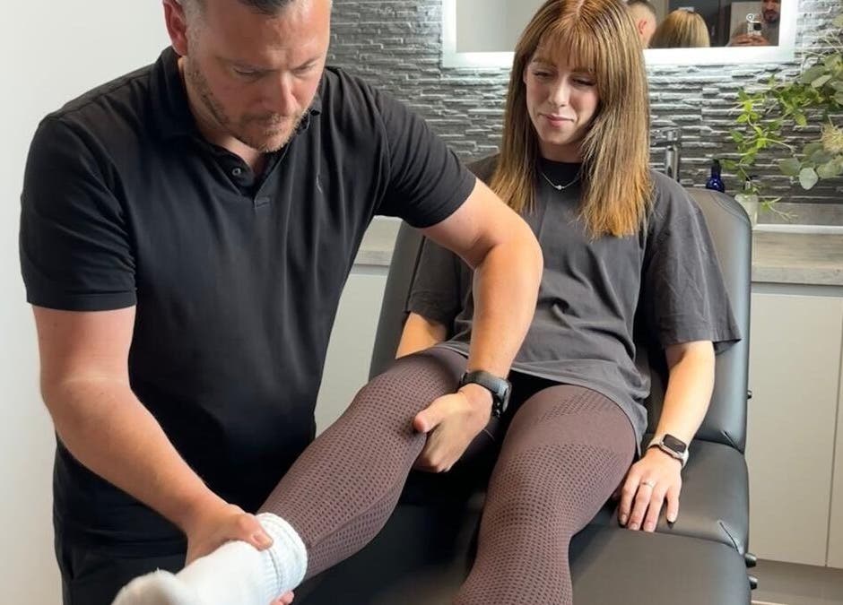 Physiotherapist treating a client's leg at First Place Physiotherapy in Fleet, England, GB clinic room.