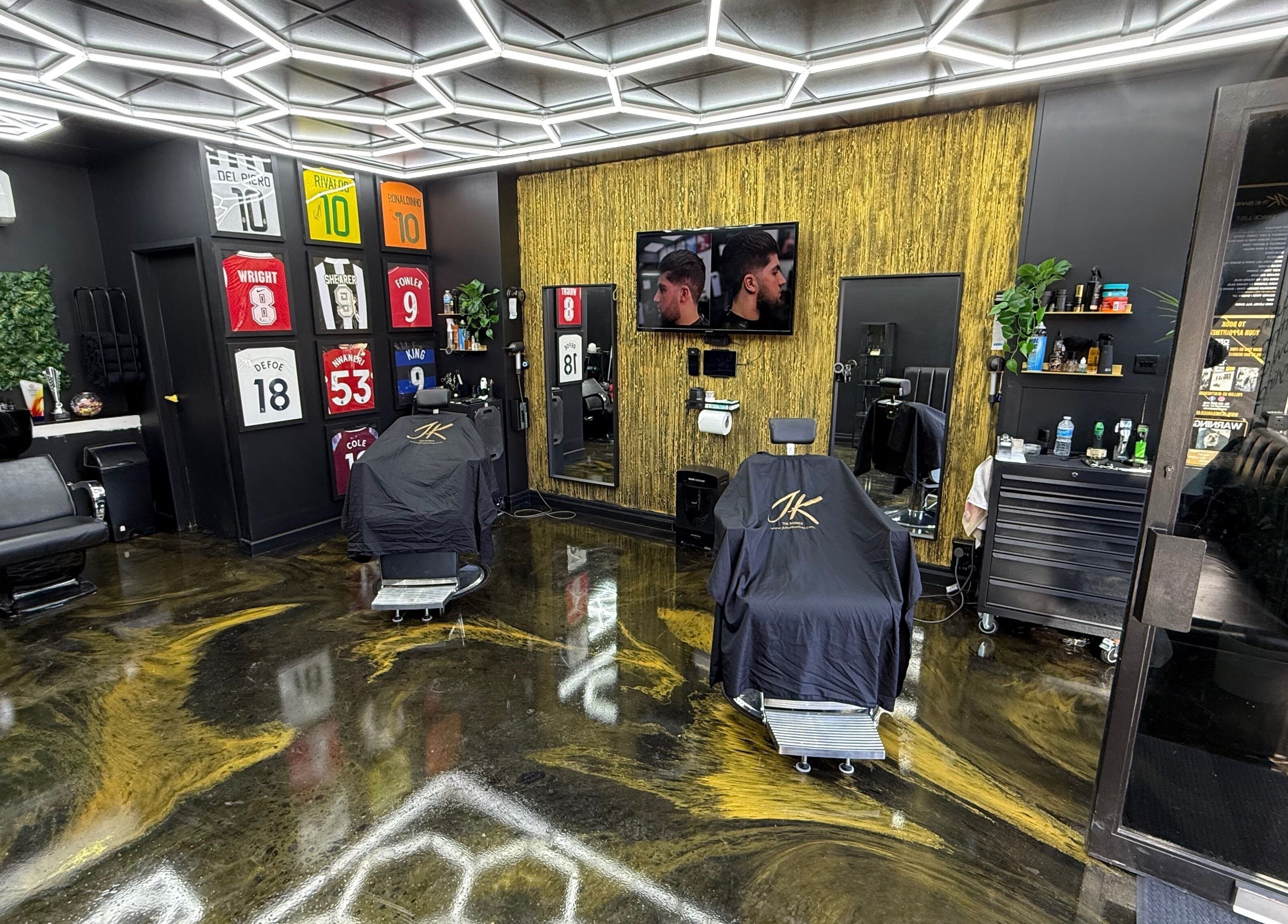 Interior of Jk The Barber Studios Limited, Edgware, England. Modern barber chairs and decor with jerseys on the wall.