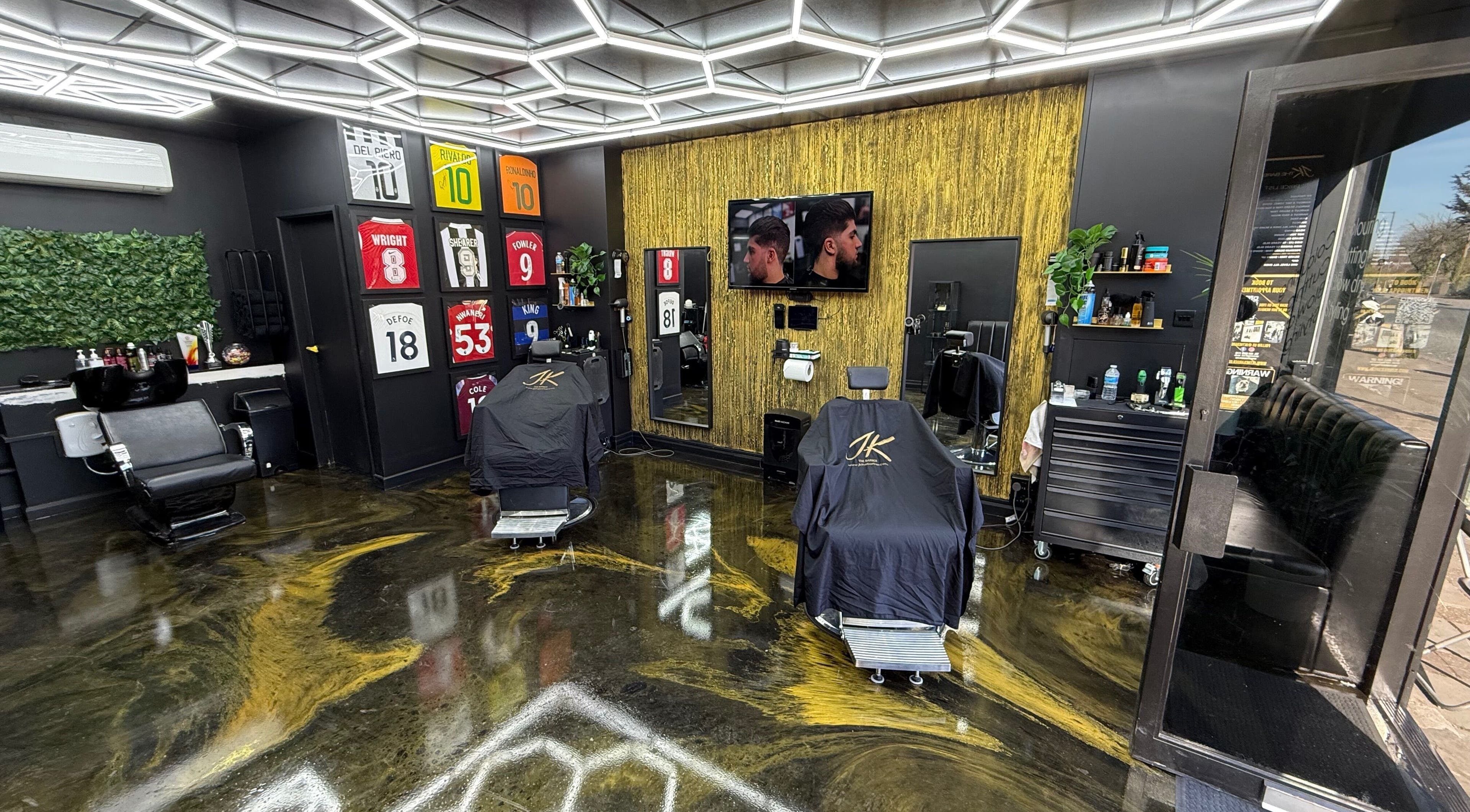 Interior of Jk The Barber Studios Limited, Edgware, England. Modern barber chairs and decor with jerseys on the wall.