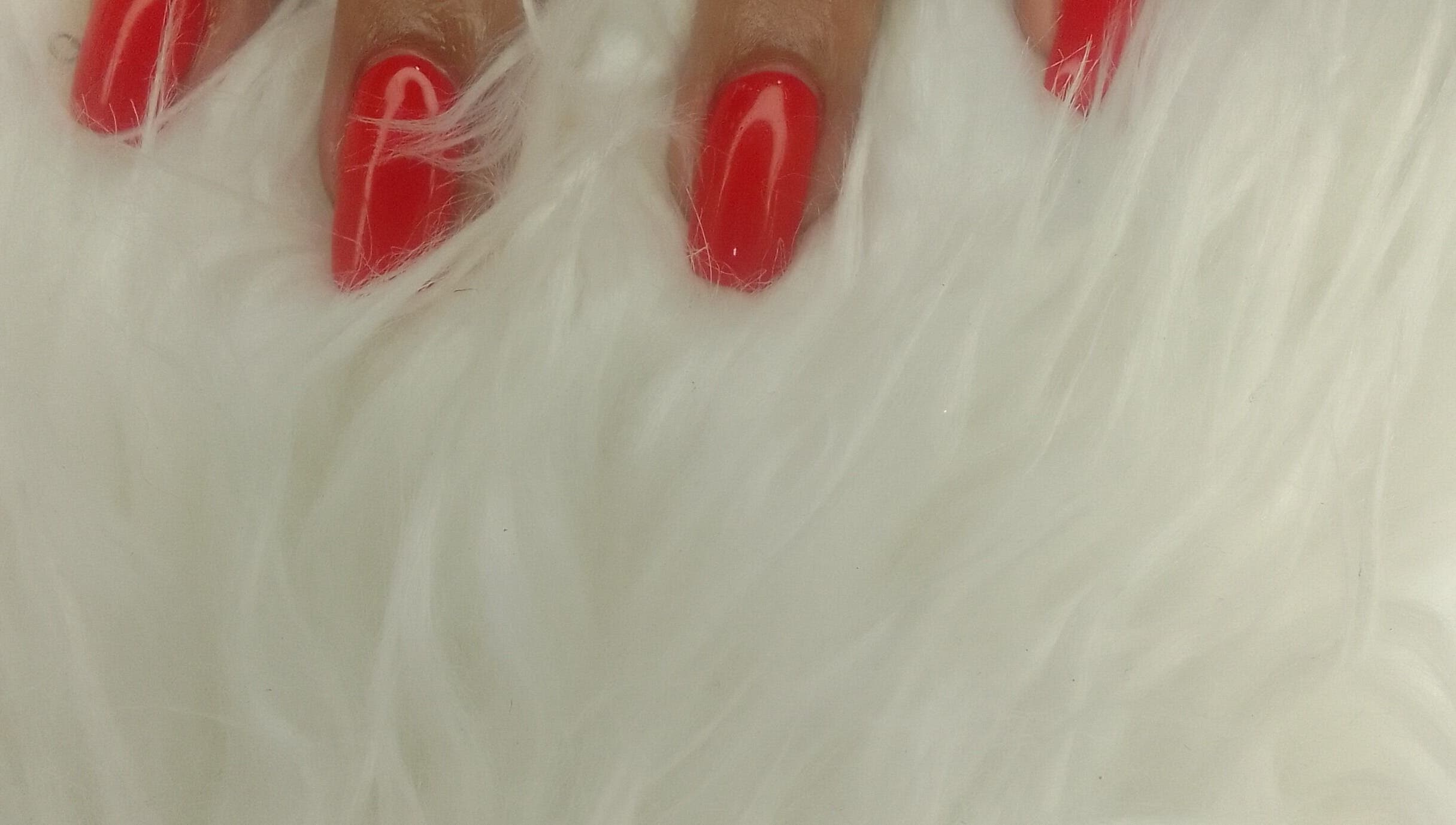 Vibrant red nails on a white fur at Sharlon Beuti Bar, Cape Town, Western Cape, ZA.
