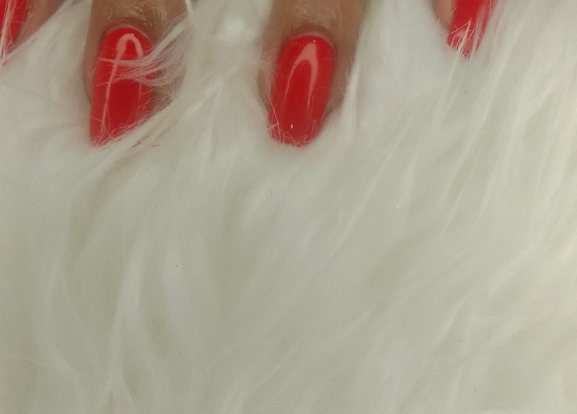 Vibrant red nails on a white fur at Sharlon Beuti Bar, Cape Town, Western Cape, ZA.