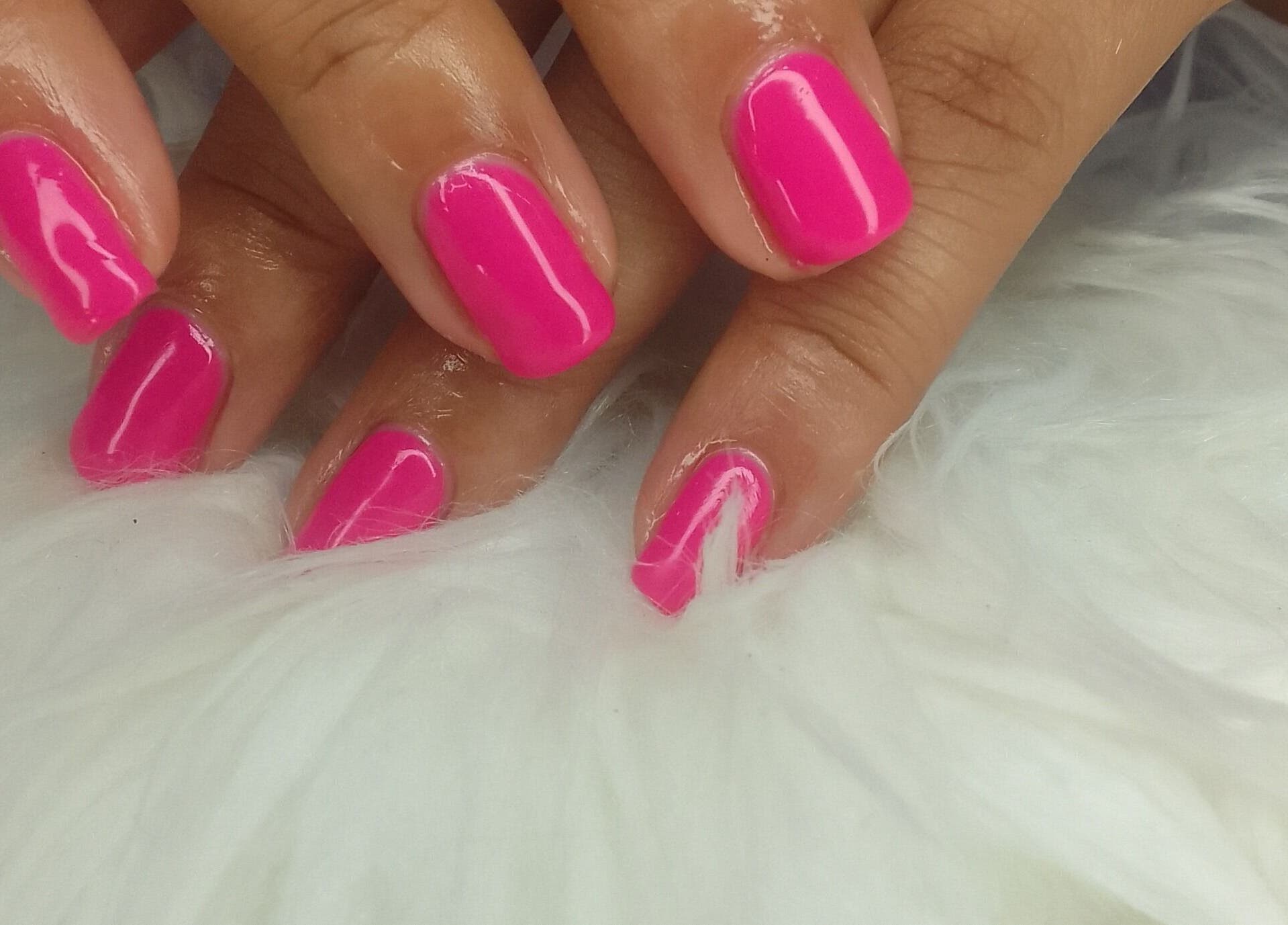 Bright pink manicure at Sharlon Beuti Bar, Cape Town, Western Cape, ZA on a fluffy white background.
