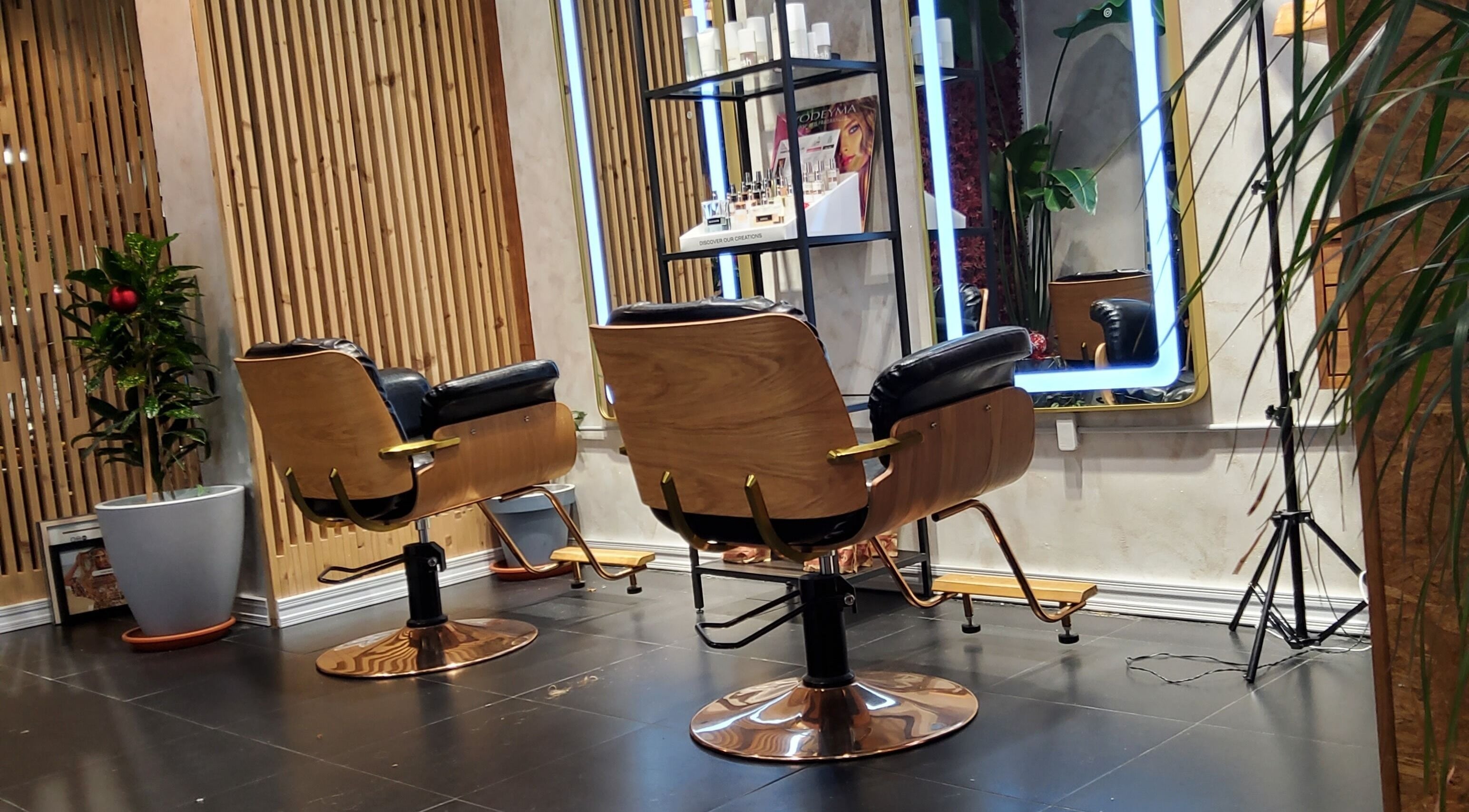 Interior del Flowerfall Organic Hair Salon en Madrid, con sillas elegantes y espejos iluminados.