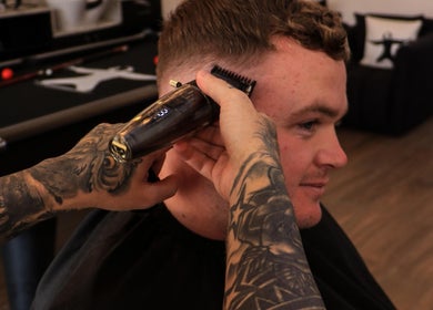 Tattooed barber gives stylish haircut at Sweeney Todds Barbers, Arjan, Dubai, AE.
