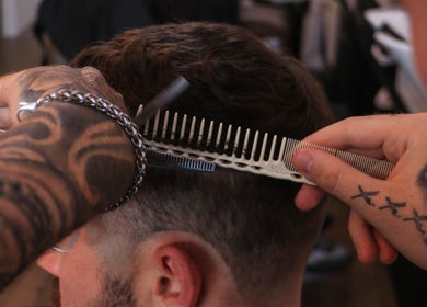 Barber cutting hair at Sweeney Todds Barbers, Arjan, Dubai, AE with precision comb and scissors.