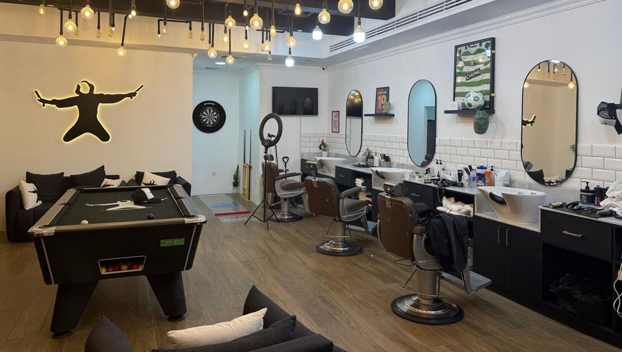 Modern interior of Sweeney Todds Barbers in Arjan, Dubai with styling chairs and billiards, offering a luxurious experience.