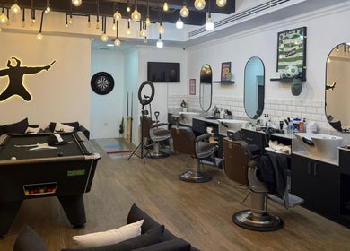 Modern interior of Sweeney Todds Barbers in Arjan, Dubai with styling chairs and billiards, offering a luxurious experience.