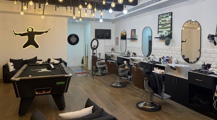Modern interior of Sweeney Todds Barbers in Arjan, Dubai with styling chairs and billiards, offering a luxurious experience.