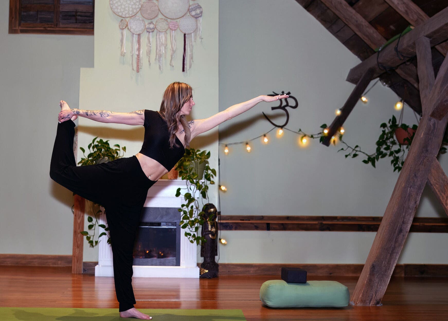 Woman practicing yoga at Connected LLC, Readfield, Maine, US. Warm ambiance with plants and wooden beams.