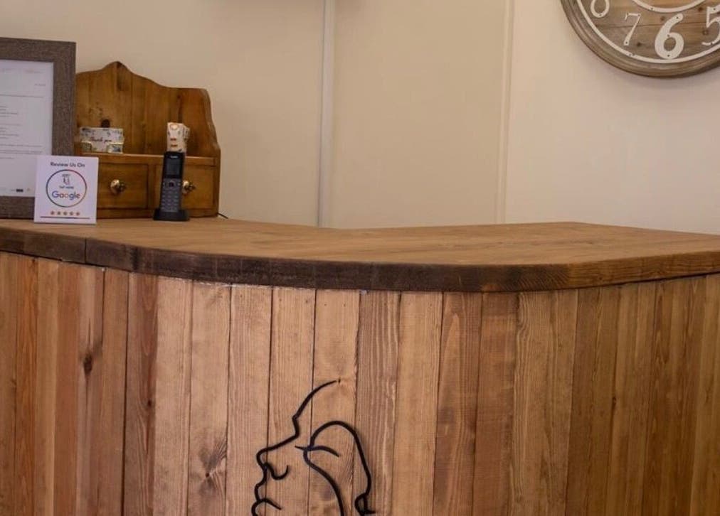 Wooden reception desk at Look at You, Poole, England, GB with rustic decor and wall clock.