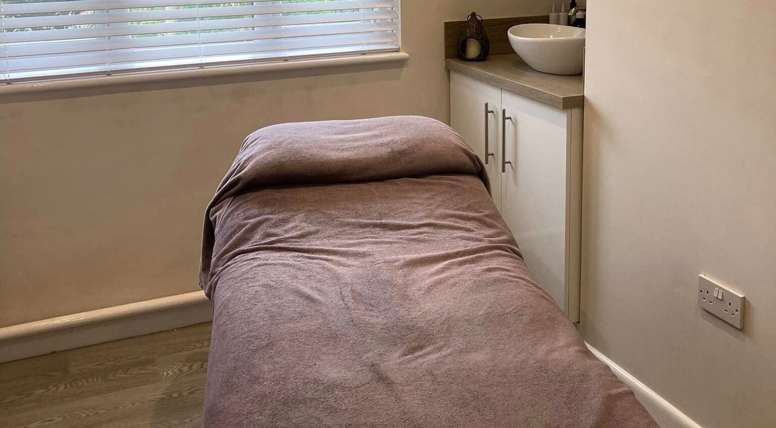 Relaxing massage room at Healthwell Clinic, Cowes, England, GB with a soft treatment bed and calming decor.