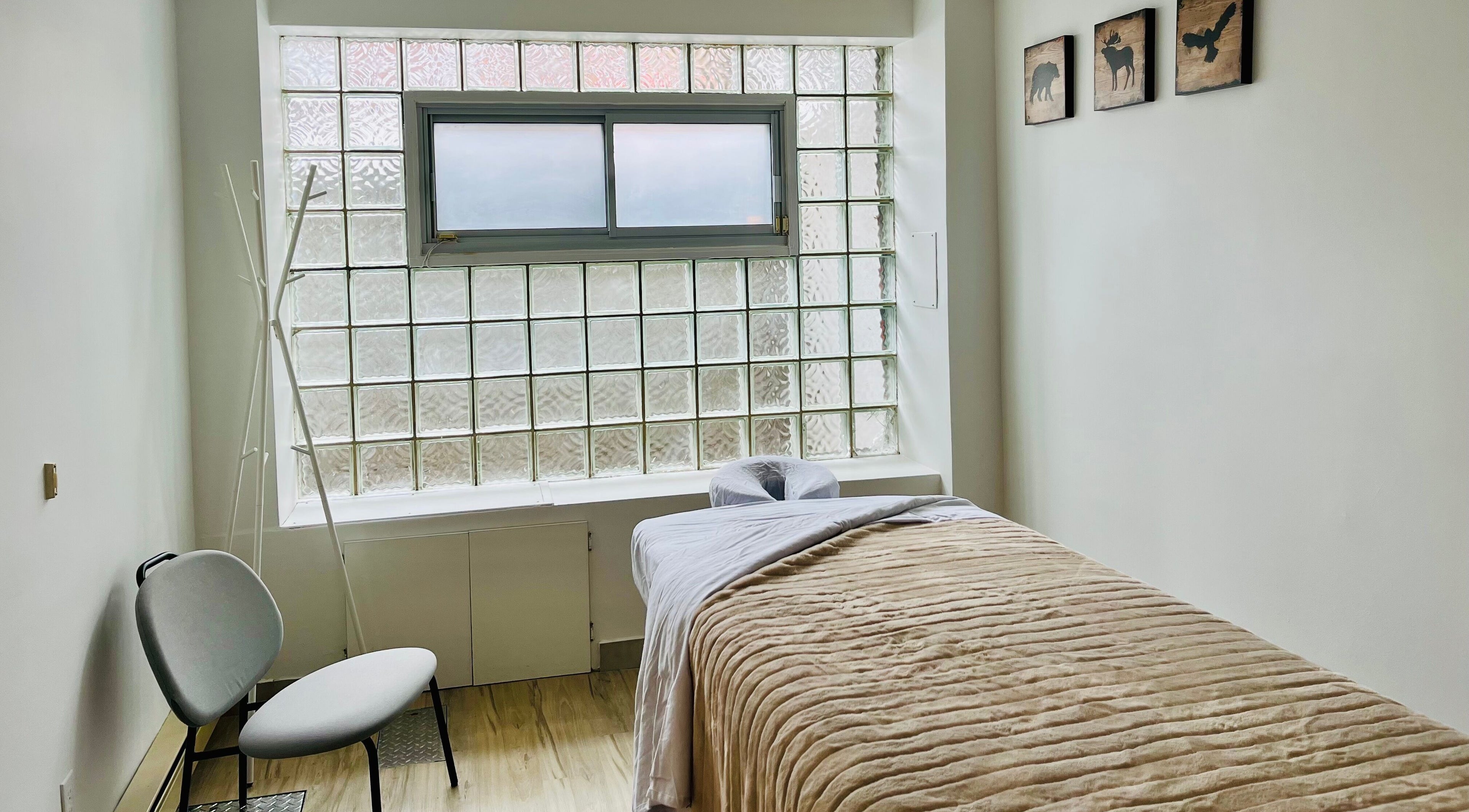 Massage room at Massage Tête à Pieds, Montréal, Québec, CA with a bed, chair, and frosted window.