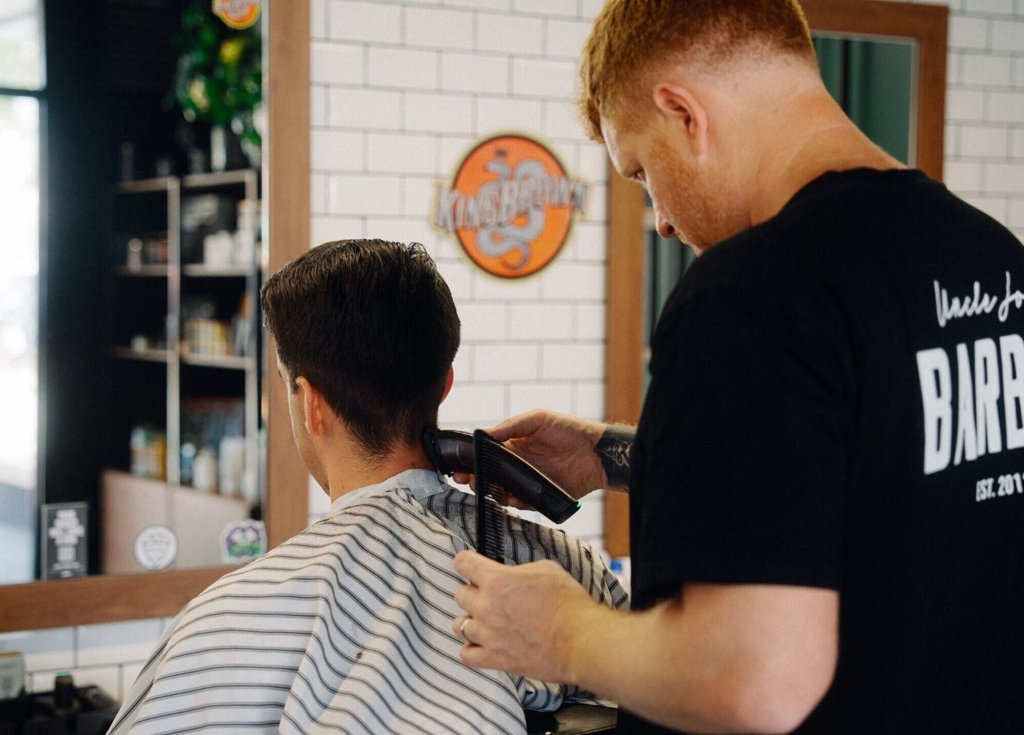 A barber trimming a client's hair at Uncle Joe's Barber - Fremantle, Western Australia, AU.