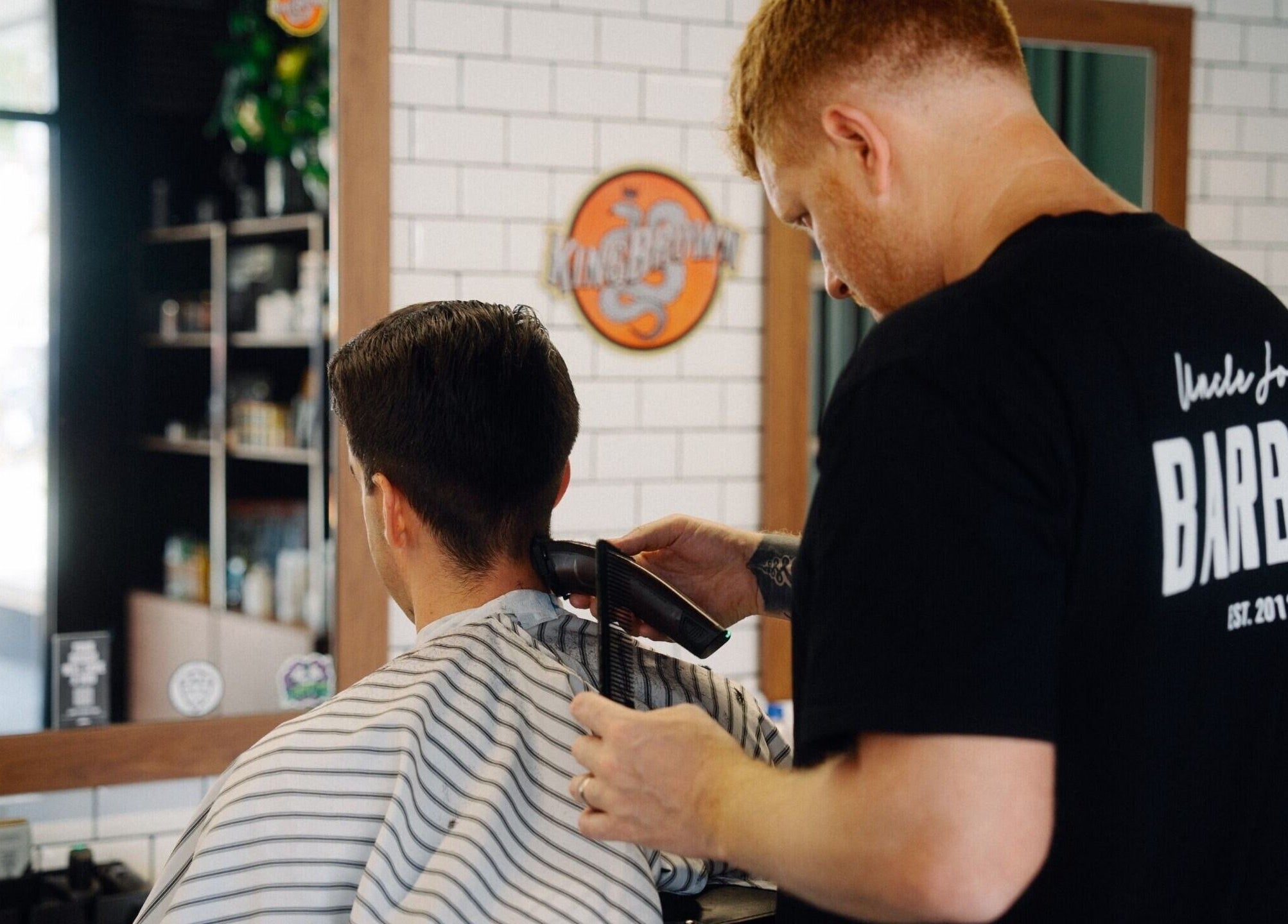 A barber trimming a client's hair at Uncle Joe's Barber - Fremantle, Western Australia, AU.