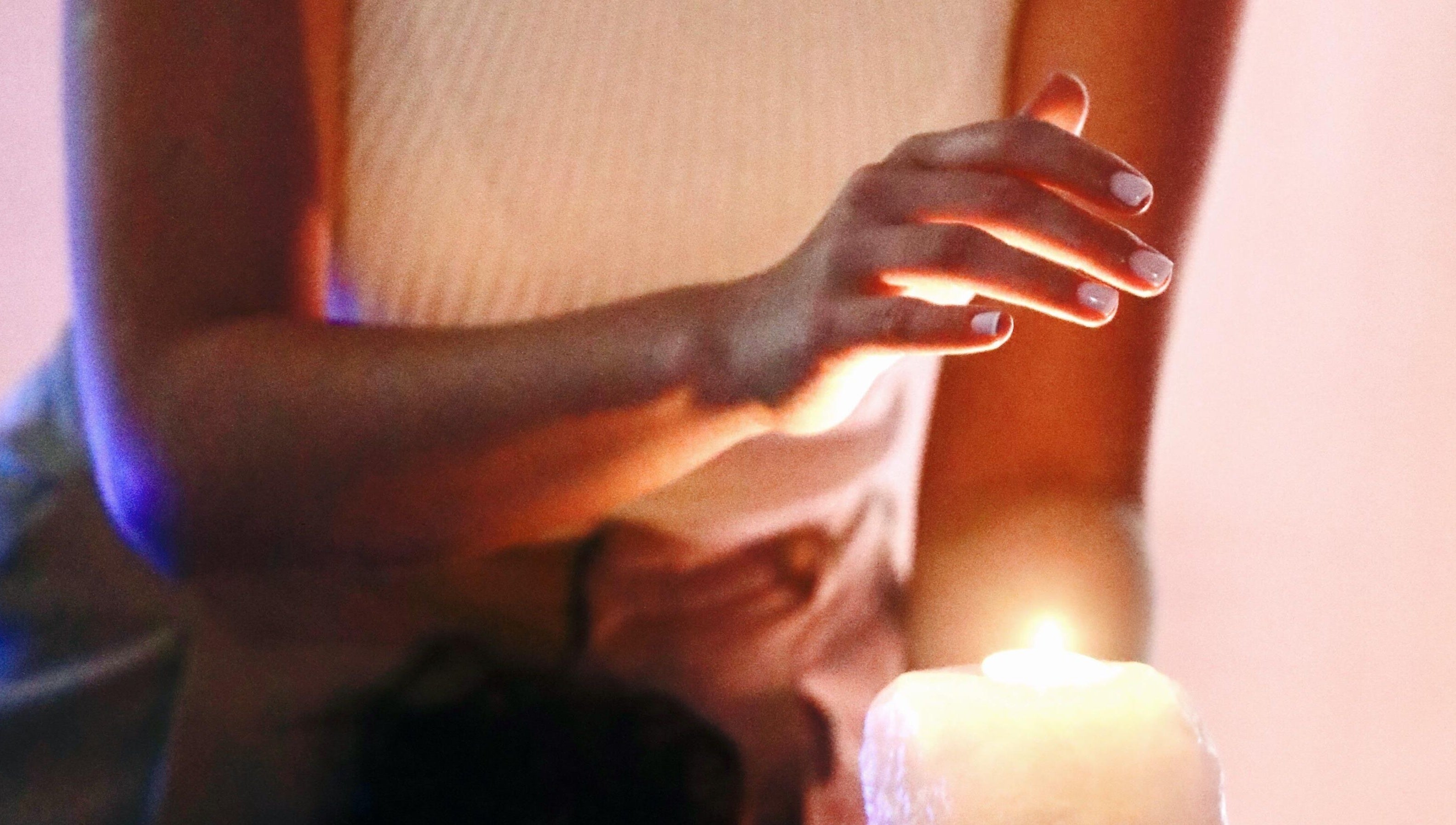 Hand gracefully hovering over a lit candle at Con Calma, Elda, Comunidad Valenciana, ES. Tranquil ambiance.