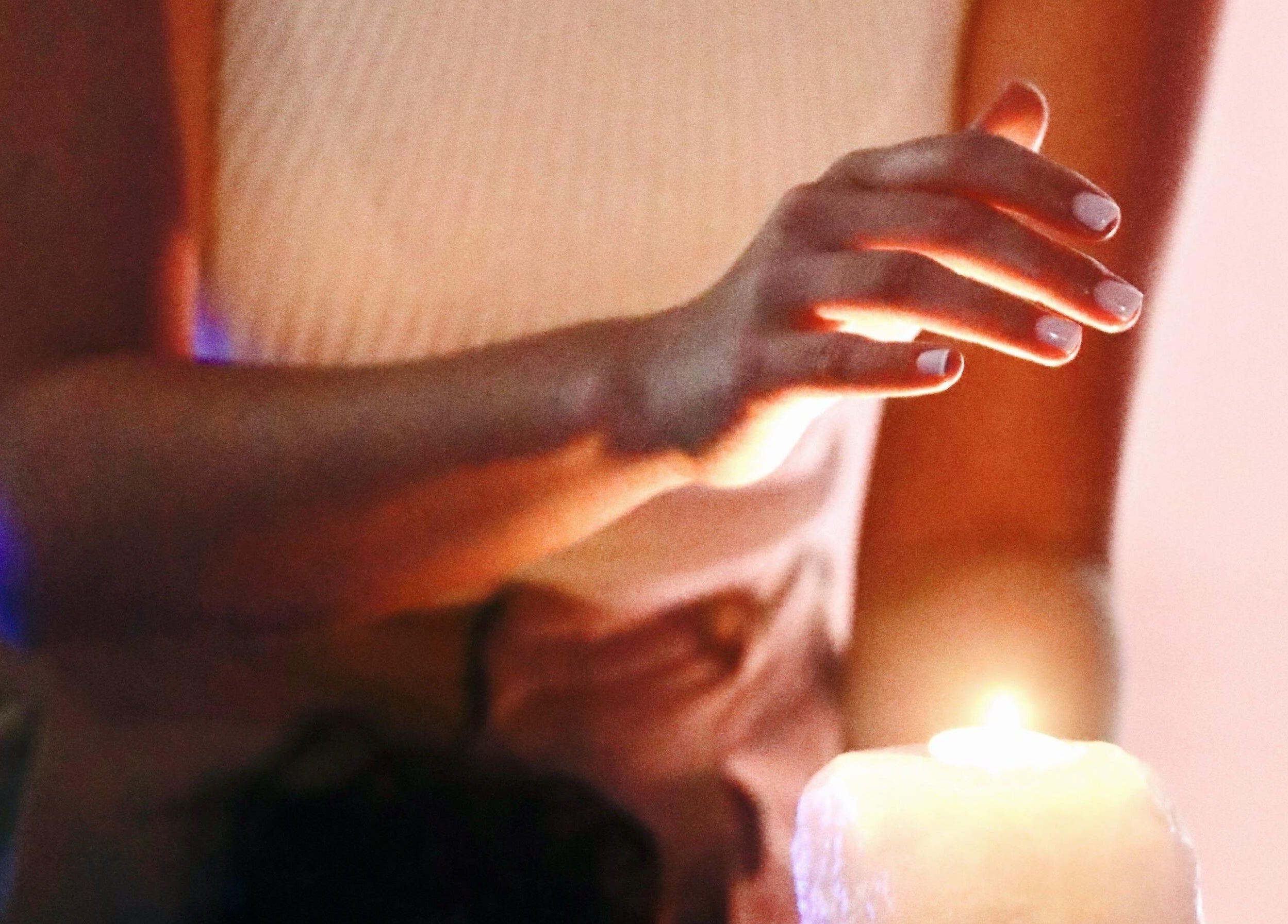 Hand gracefully hovering over a lit candle at Con Calma, Elda, Comunidad Valenciana, ES. Tranquil ambiance.